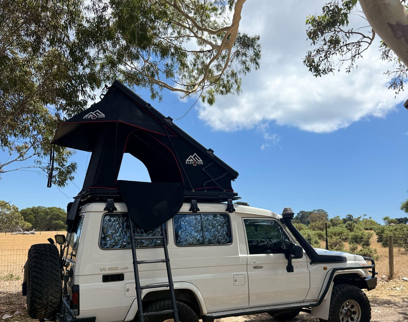 White Landcruiser with a rooftop tent in a natural setting